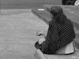 Señora pidiendo limosna con la mano extendida en la calle